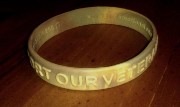 A desert camouflage bracelet for veterans from the VA with crisis support information imprinted on the inside surface.