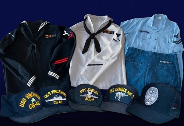 This collection of uniforms shows four official shipboard navy ball caps, authorized for wear with utility uniforms (such as the now-defunct dungaree set on the right). Note the UIM patch on the right sleeve of the dress blue uniform jumper.