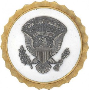 The obsolete White House Service Badge features a natural metal seal on the white field. When this bade was retired in 1964, it was replaced with the Presidential and Vice Presidential Service Badges.